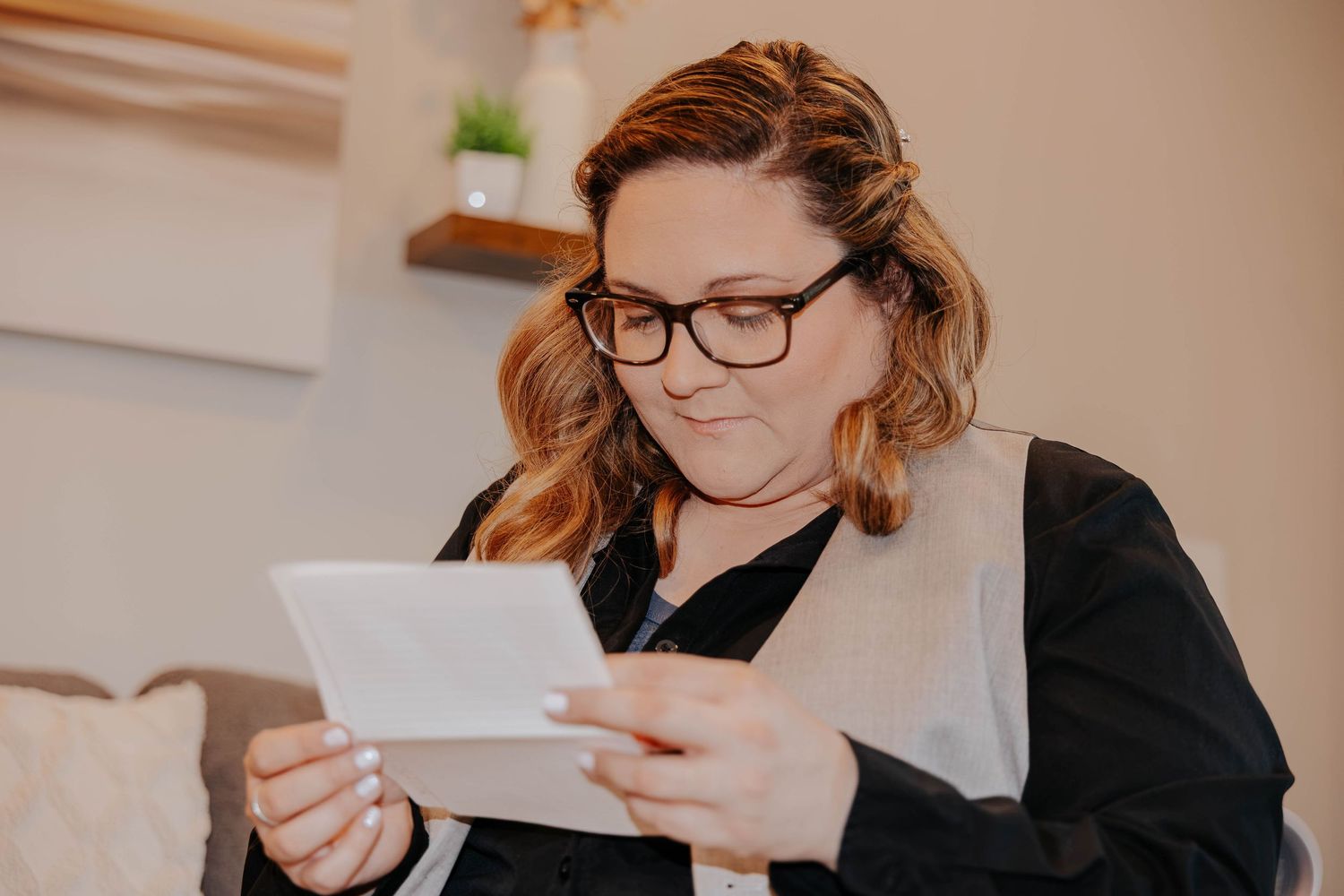 Bride wearing glasses and a black jacket reads a personal letter during intimate Northern Michigan elopement preparations.