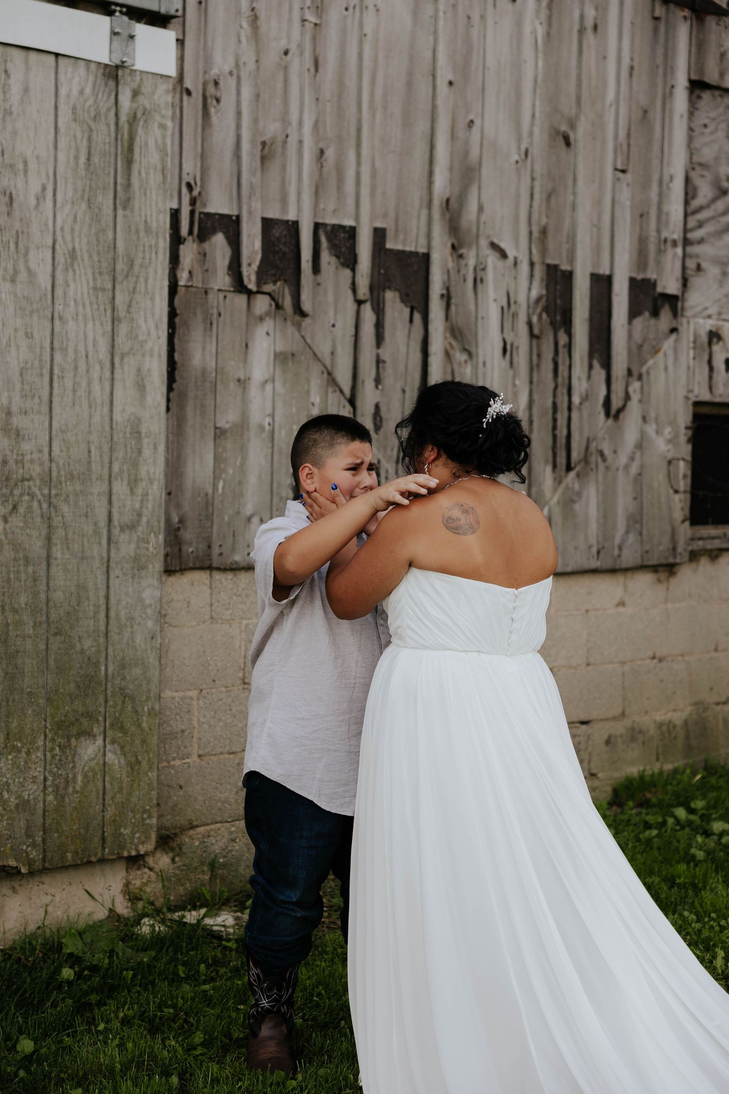 Romantic bride and groom portrait beside a weathered wooden barn at a rustic wedding in Sparta, Michigan.