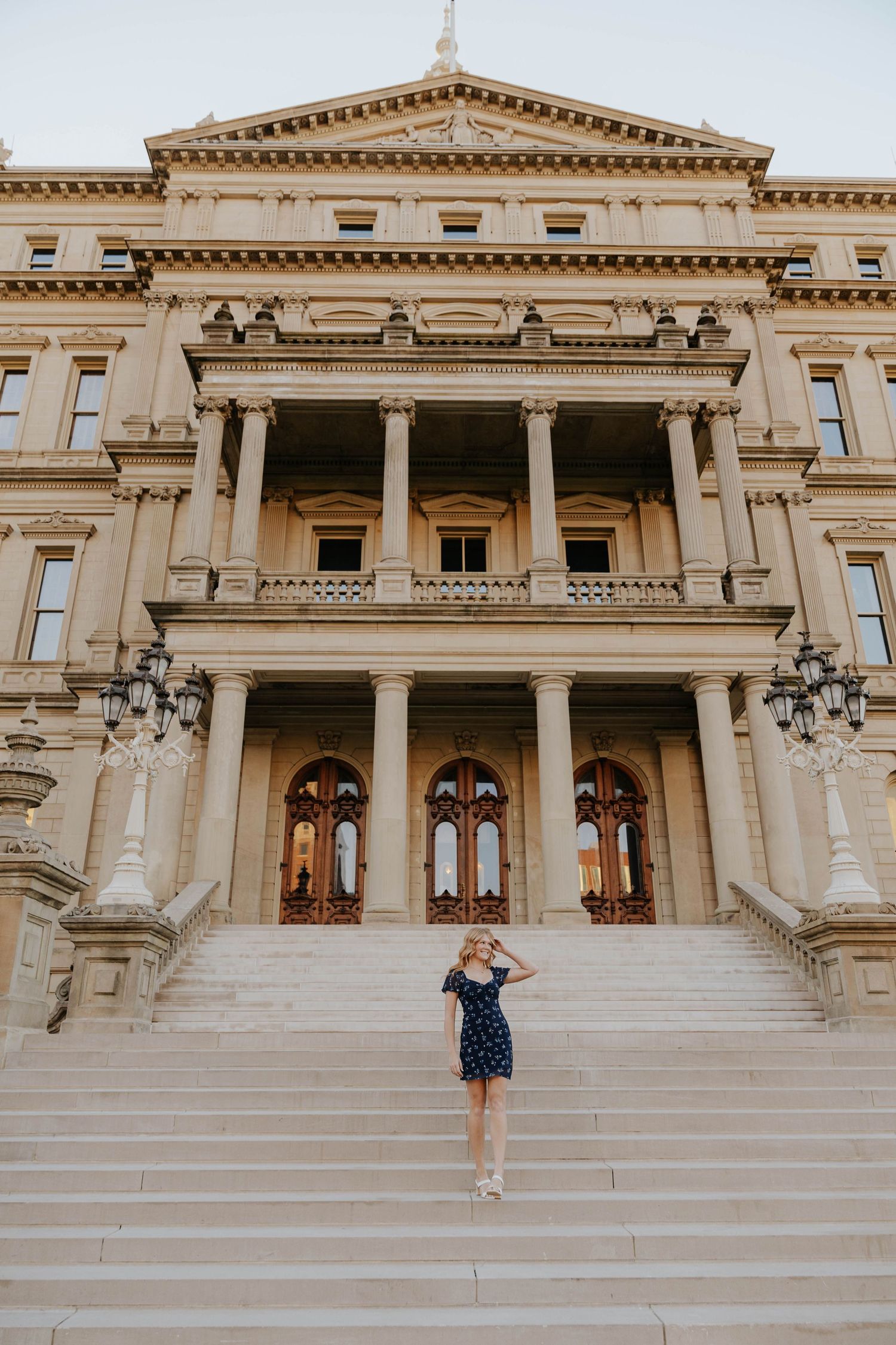 Senior portrait photography at the Michigan State Capitol in Lansing, featuring a graduate standing on the grand stone steps.