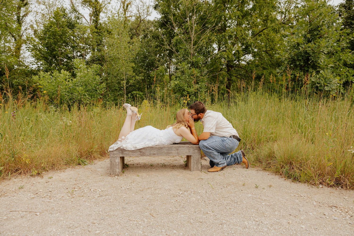 Romantic garden engagement photo of a couple sitting together on a bench surrounded by wildflowers and greenery in Michigan.