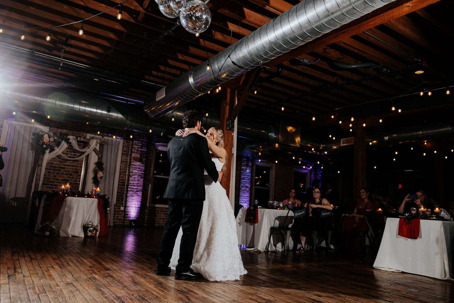 Bride and groom sharing their first dance at a warmly lit wedding reception at The Record Box In Battle Creek, Michigan.