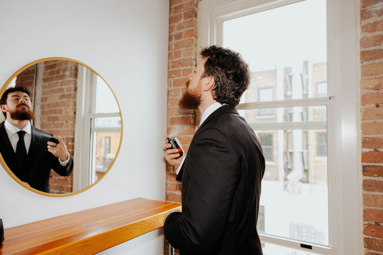 Groom adjusting his tie in a mirror before his wedding ceremony at Record Box Loft in Battle Creek, Michigan.