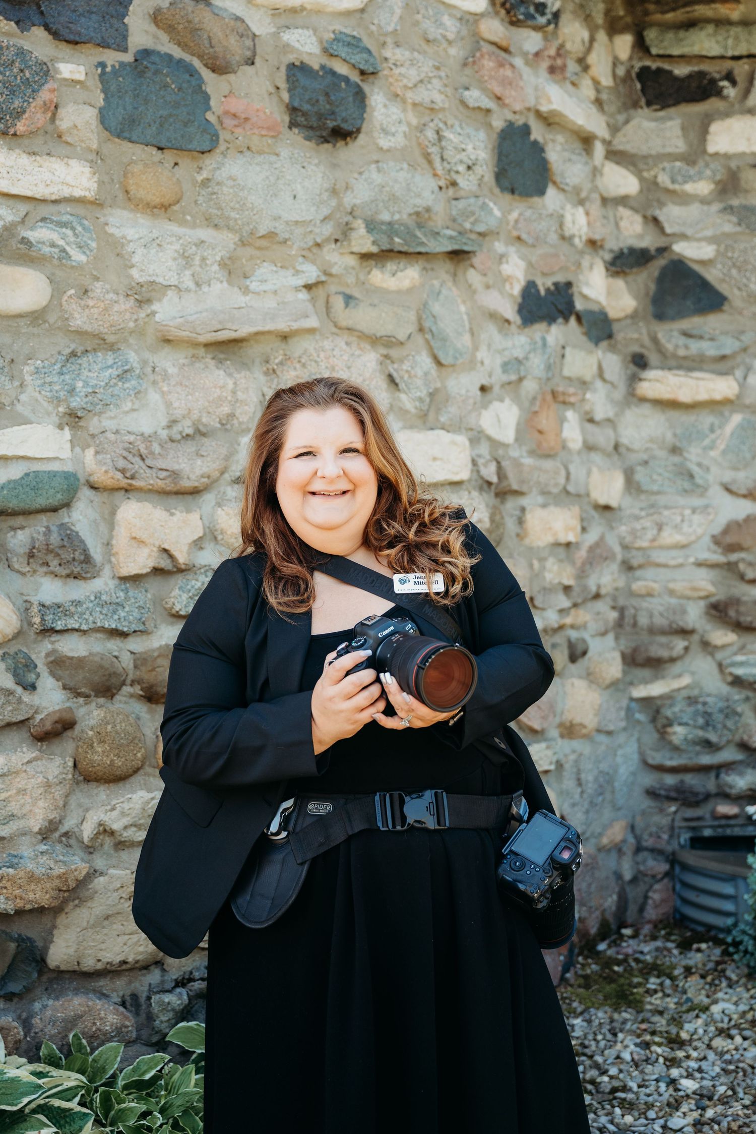 Woman with red hair smiles while holding her camera against a textured stone wall at Castle Farms in Charlevoix, Michigan.
