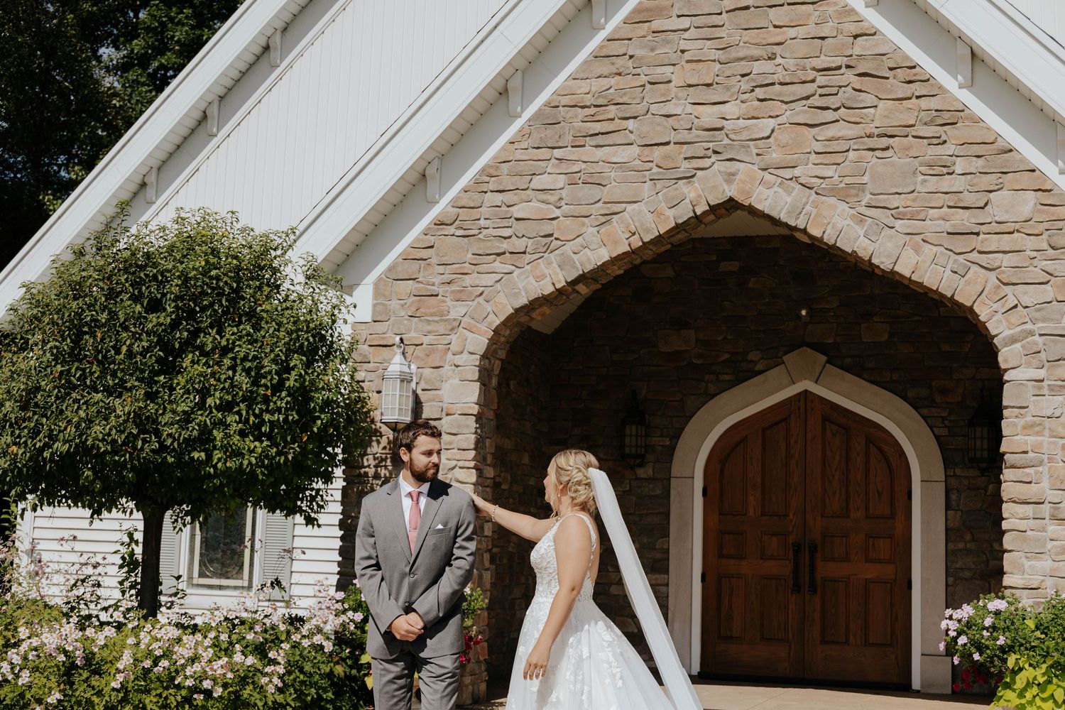 Elegant bride and groom portrait outside a stone chapel-style building at Hawk Hollow in Lansing, Michigan.