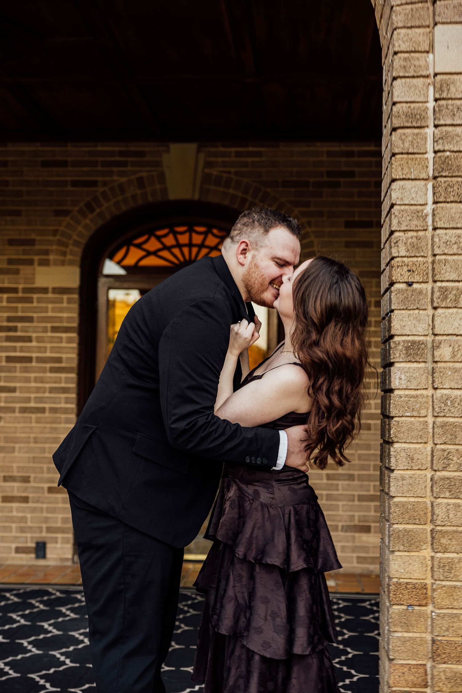 Elegant engagement portrait of a couple embracing beneath the stone archway at Felt Estate in Saugatuck, Michigan.