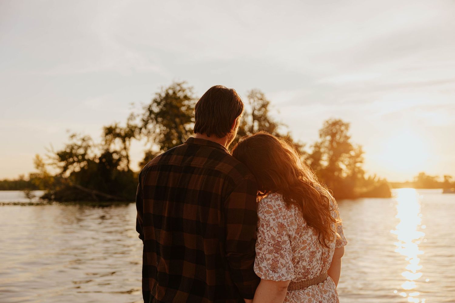 Romantic Lake Odessa engagement photo of a couple embracing by the water at golden hour, with warm sunset light reflecting on the lake.
