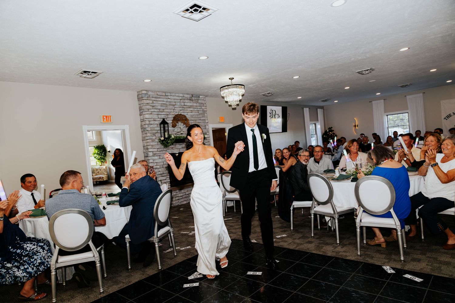 Newlyweds making their grand entrance into their wedding reception at Hidden Oak Manor in Indiana as guests celebrate.