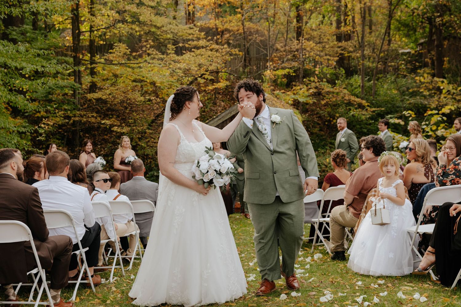 Bride and groom exchanging vows during a romantic outdoor wedding ceremony surrounded by guests at Bowen Mills in Middleville, Michigan.