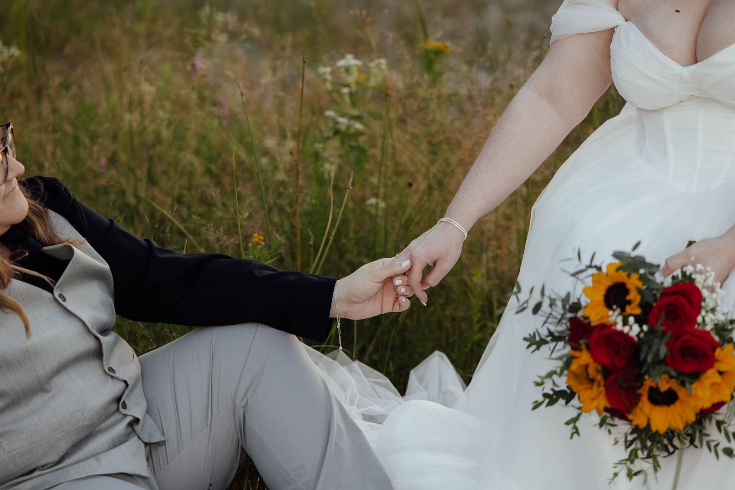Close-up of an eloping couple holding hands beside a colorful bridal bouquet during their intimate Northern Michigan wedding.