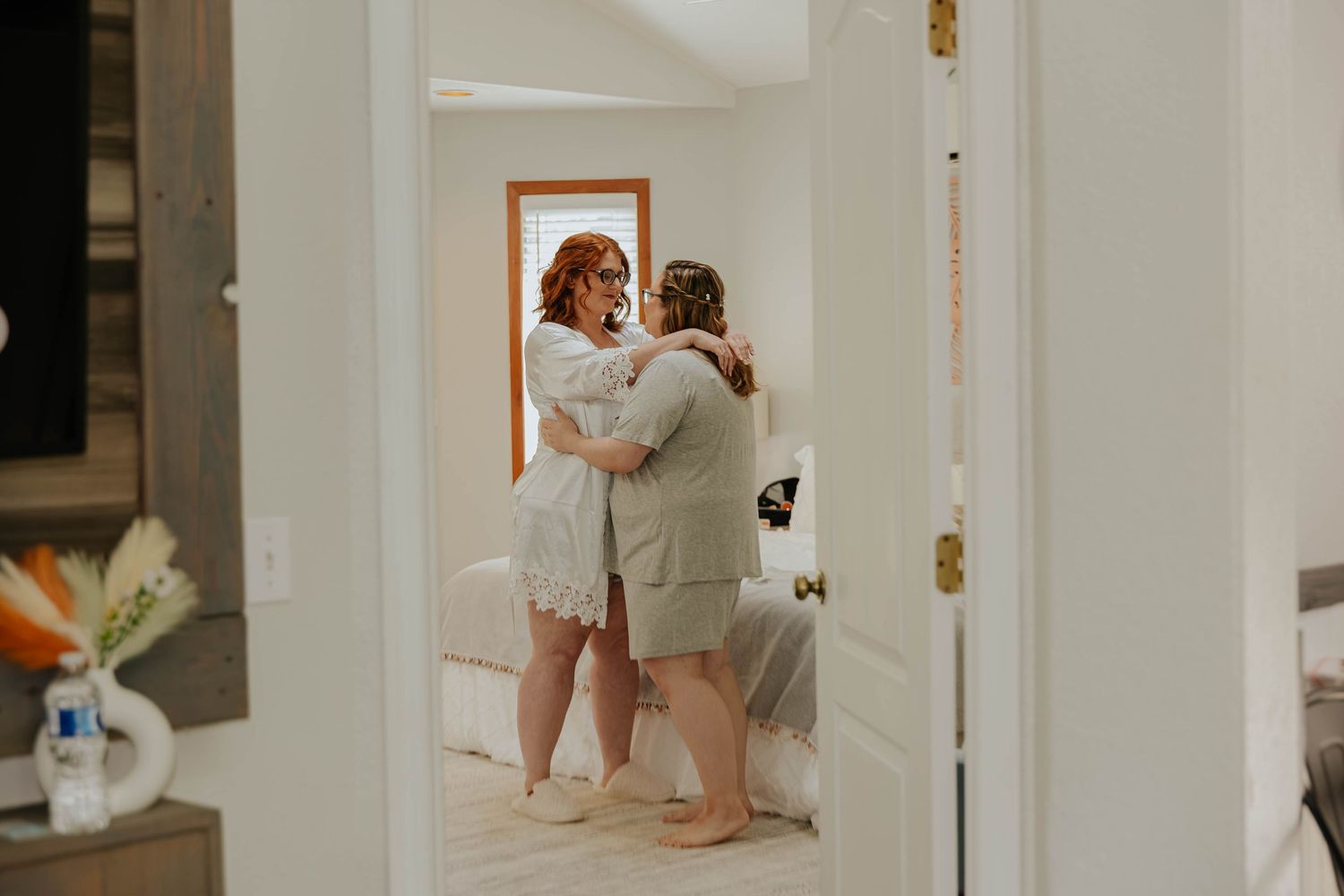 Two women share an emotional embrace in a doorway during the getting-ready moments of a Northern Michigan elopement.