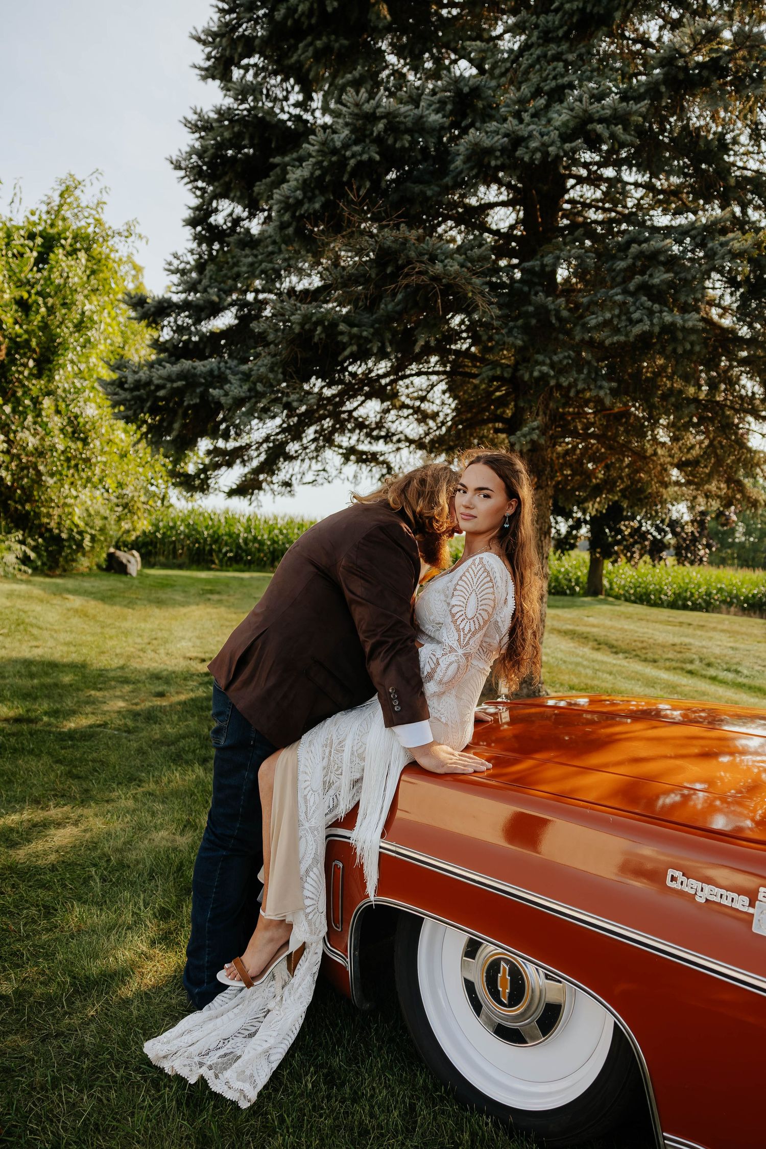 Bride and groom share a romantic embrace beside a vintage red pickup truck at The Gather wedding venue in Allegan, Michigan.