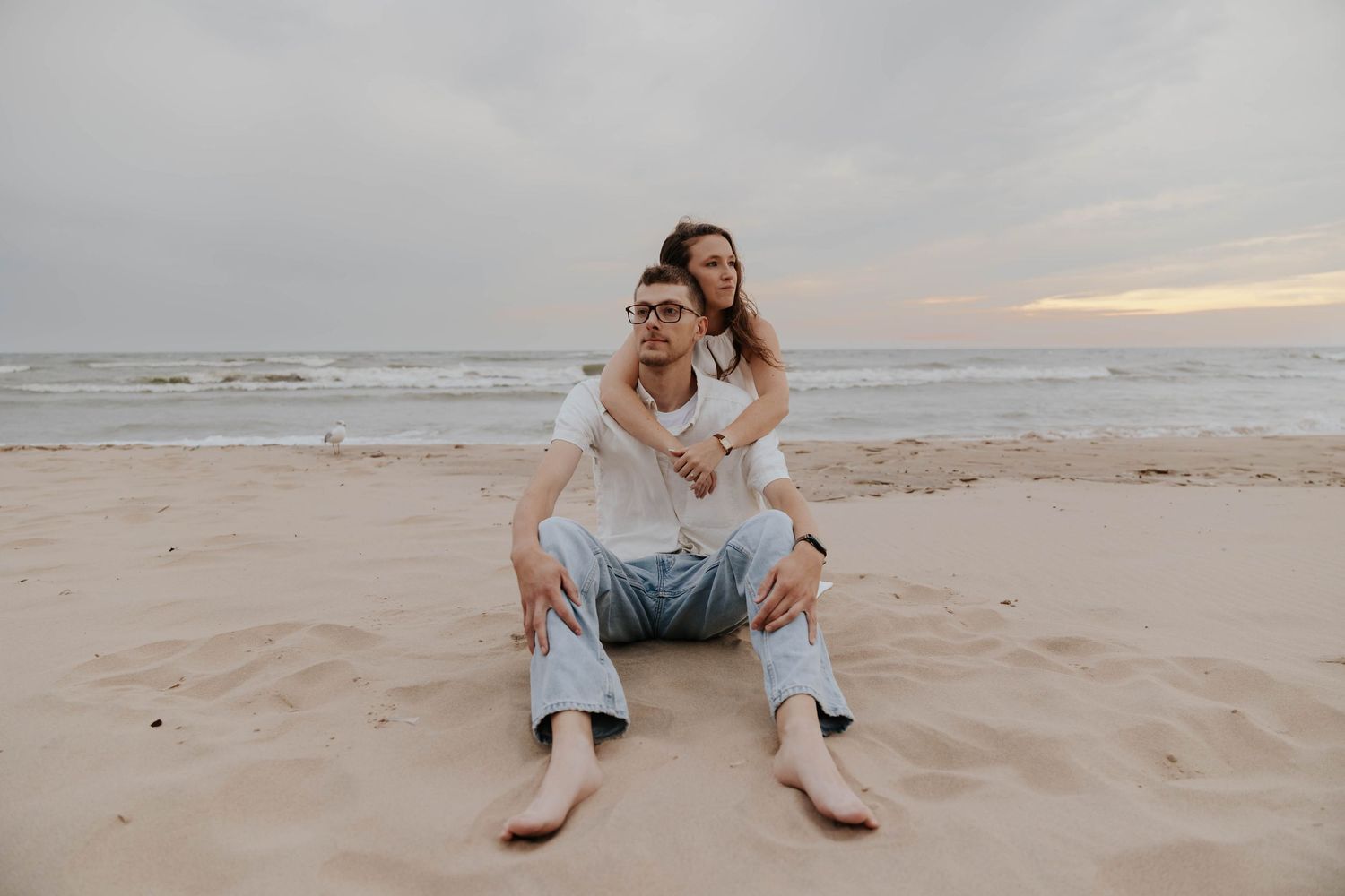 Romantic Holland, Michigan beach engagement photo of a couple embracing at the water's edge during a Lake Michigan sunset.