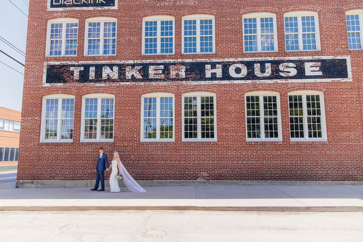 Bride and groom posing outside the historic brick Tinker House wedding venue in Indianapolis, Indiana.