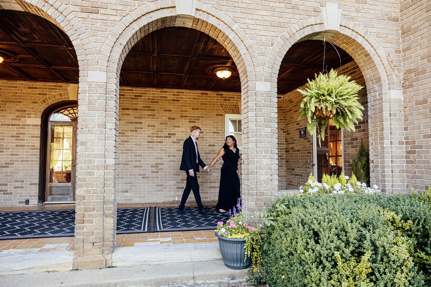 Elegant engagement portraits of a couple walking beneath the historic stone archways at Felt Estate in Michigan.