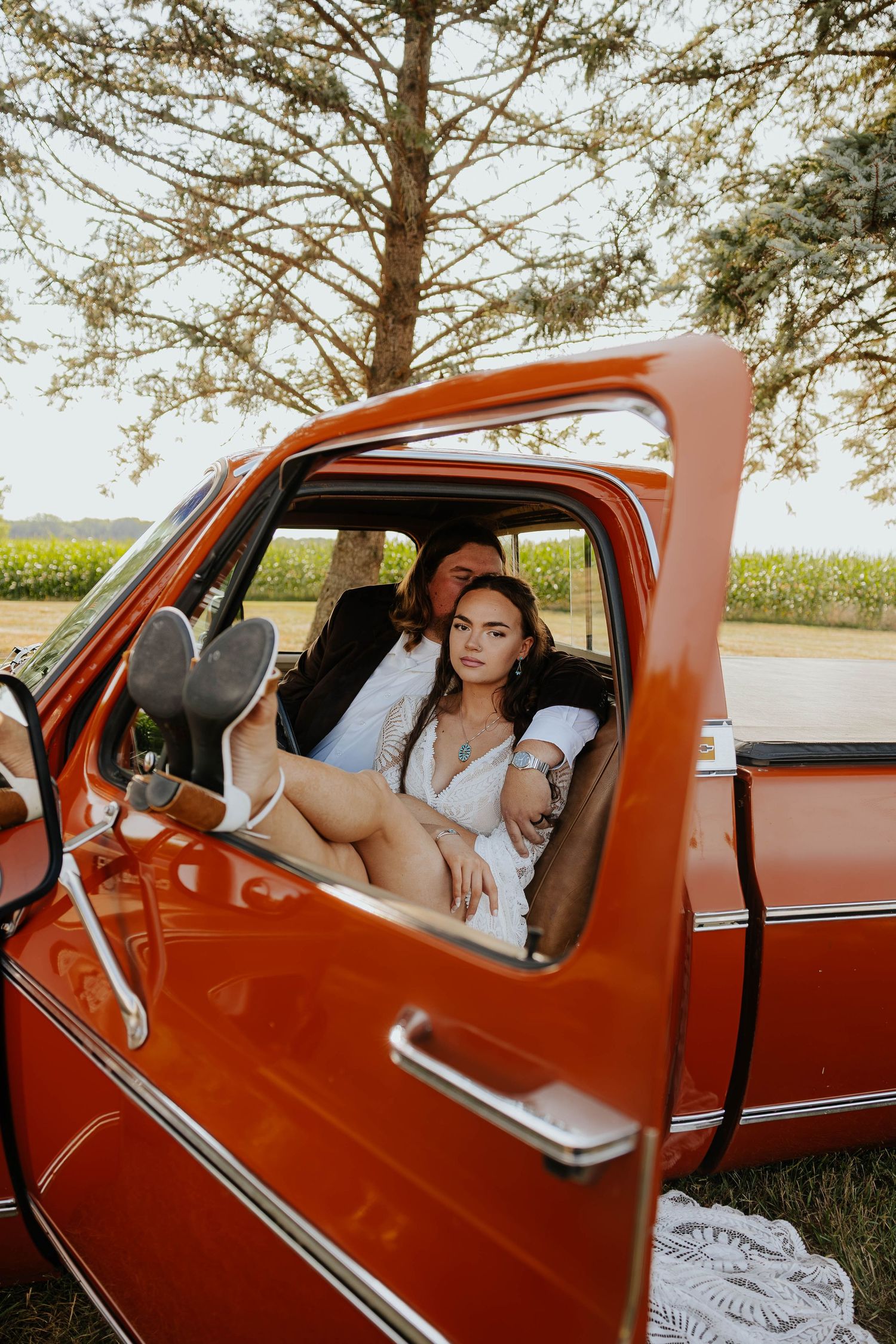 Bride smiles from the driver's seat of a vintage red pickup truck during her wedding at The Gather in Allegan, Michigan.
