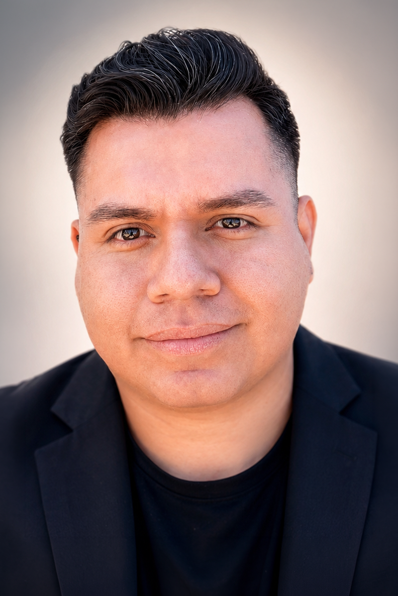 Professional headshot of a young Hispanic man in a black blazer with short dark hair, smiling confidently.