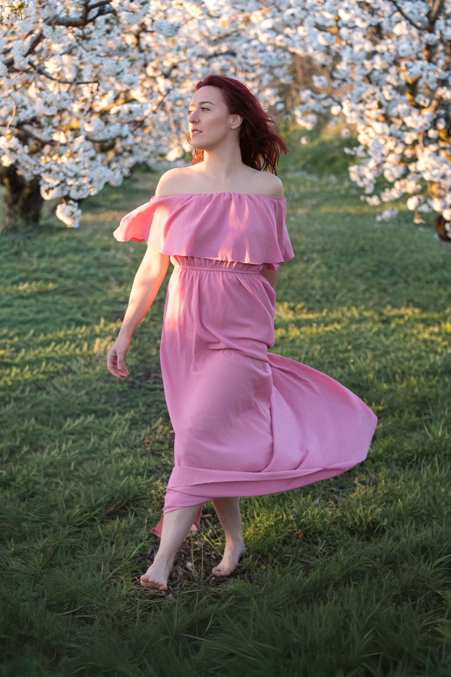 Portrait en mouvement d'une femme en robe rose lors d'une séance photo douceur dans les cerisiers en fleurs en plein air à Avignon