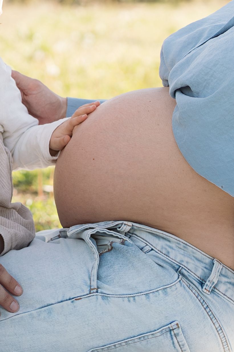 Gros plan sur le ventre d'une future maman pour une séance photo grossesse en extérieur dans les cerisiers en fleurs à Avignon