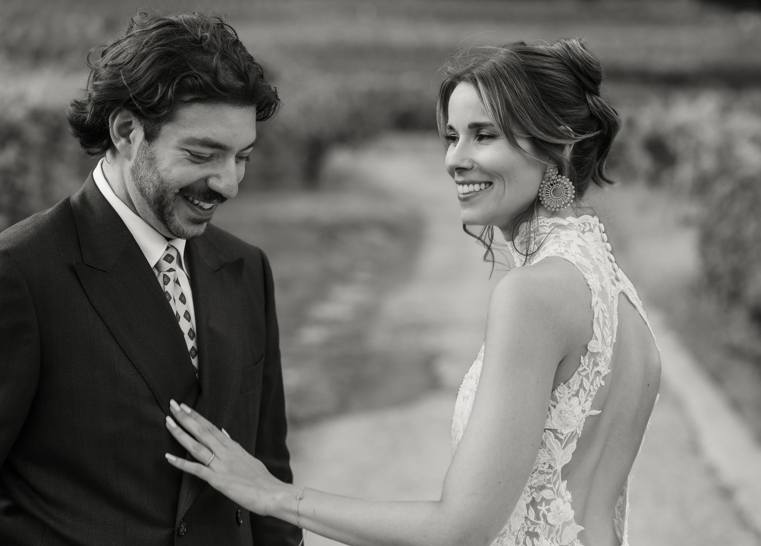 Black and white photo of smiling bride and groom sharing a joyful moment at their wedding.