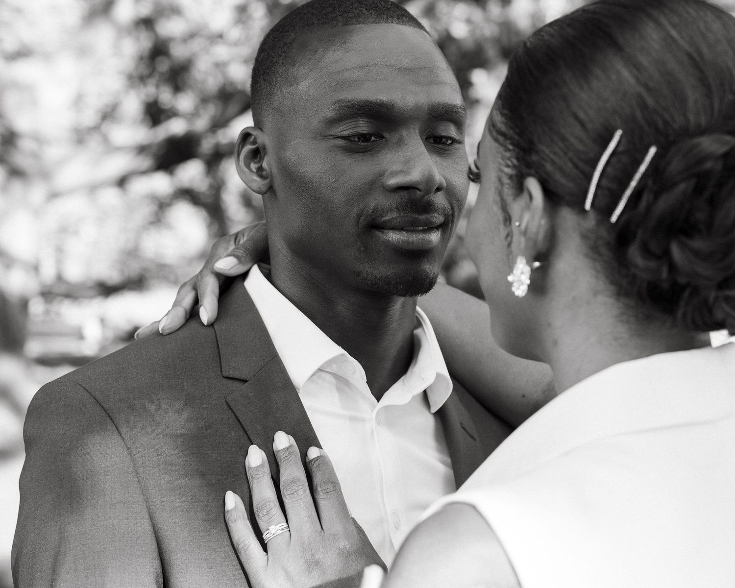 Emotional Black groom gazing at bride in black and white outdoor wedding portrait.