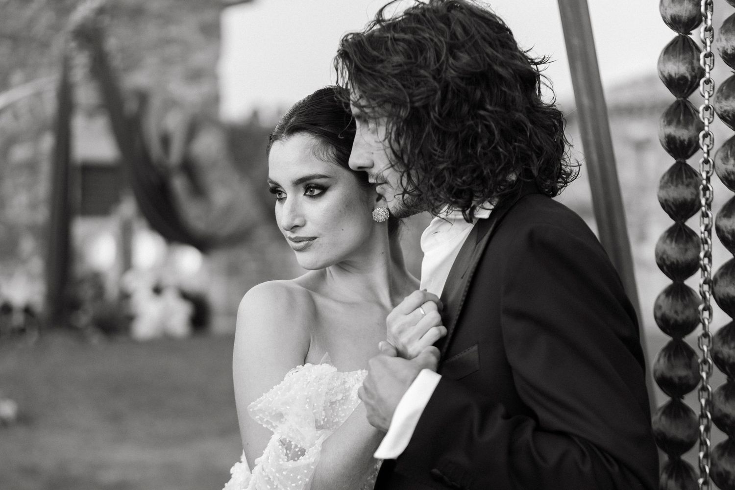 Black and white wedding photo of bride and groom in close romantic embrace, groom kissing bride's cheek.