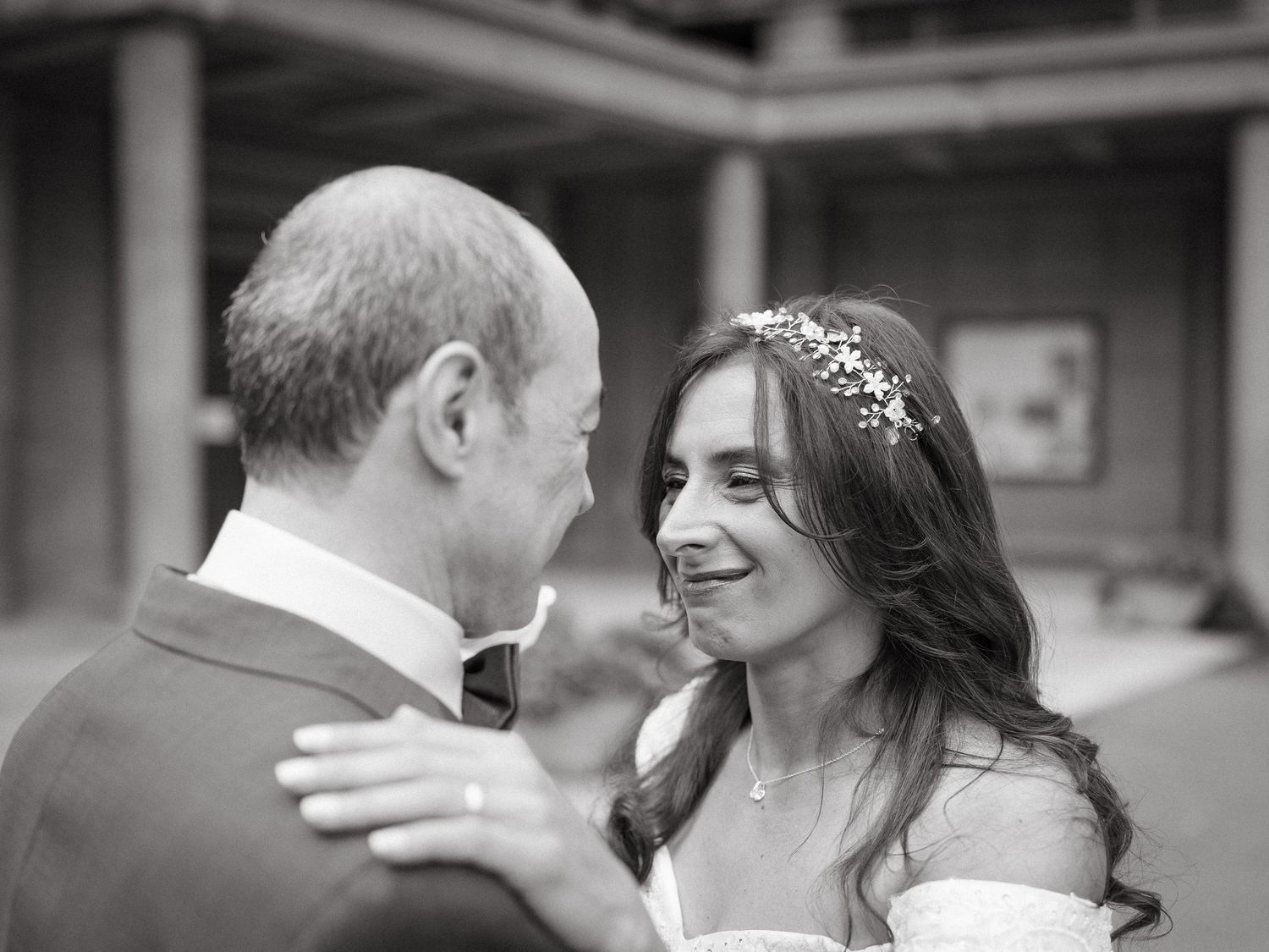 Black and white wedding photo of bride and groom sharing an intimate moment, bride wearing floral hair accessory.
