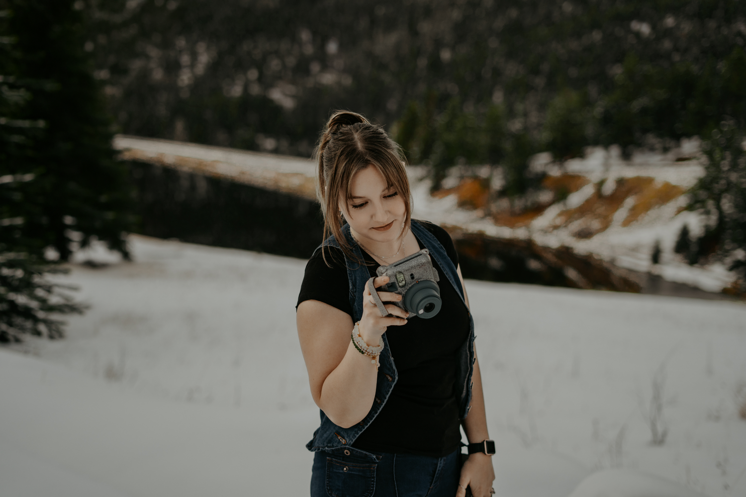 A Colorado elopement photographer captures images in a snowy mountain setting with her polaroid camera at Lake Isabel.