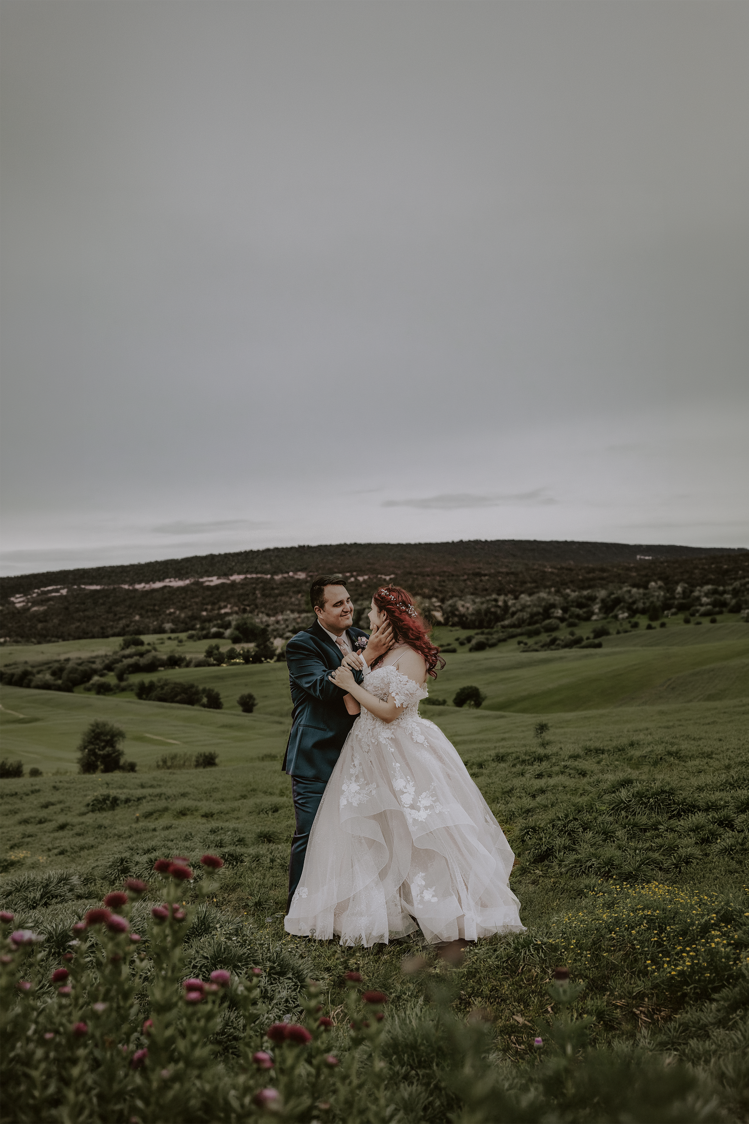 Wedding couple in Colorado dances in field of wildflowers with mountains in background.