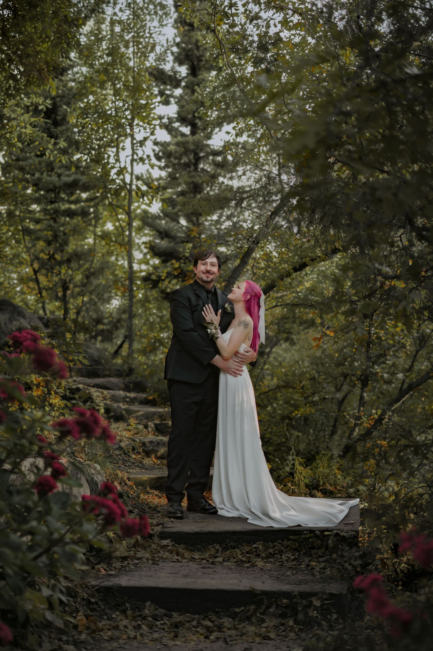 An elopement ceremony takes place on stone steps surrounded by autumn foliage and red flowers in Pueblo Mountain Park.