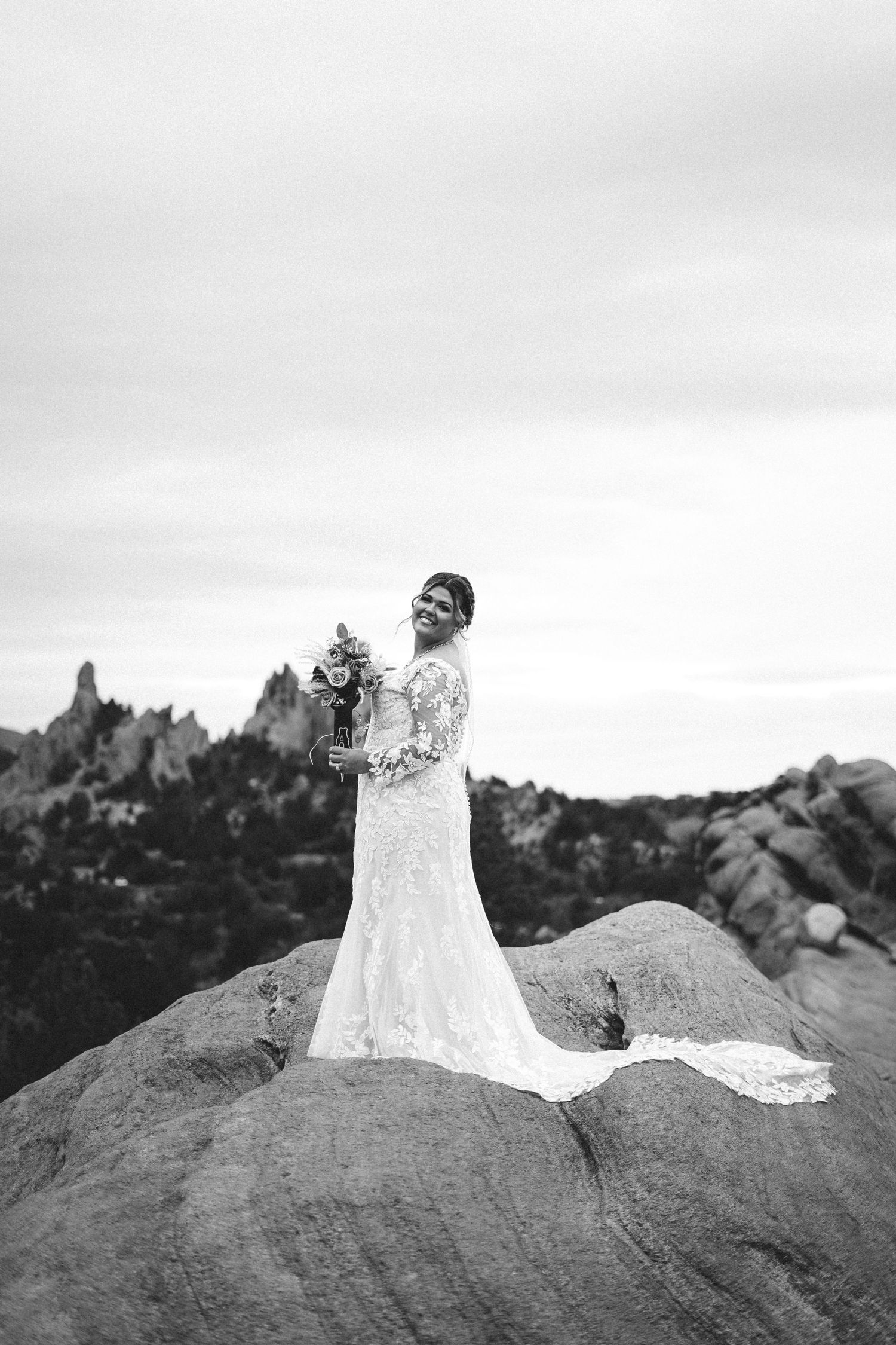 A flowing white wedding dress cascades over dramatic rock formations at Garden of the Gods in black and white.