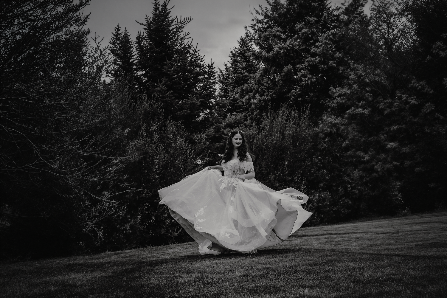 Happy bride dancing among the pine trees in her flowy wedding dress after her elopement ceremony in Colorado.