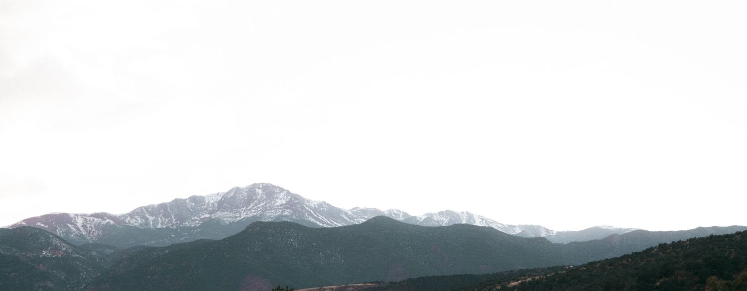 Panoramic view of snow-capped mountain range under cloudy sky at Garden of the Gods.