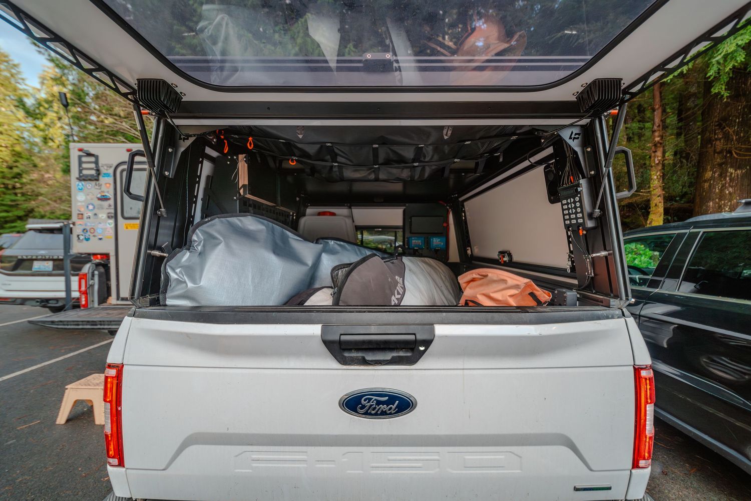 Interior view of a Ford pickup truck bed with storage compartments and camping gear.