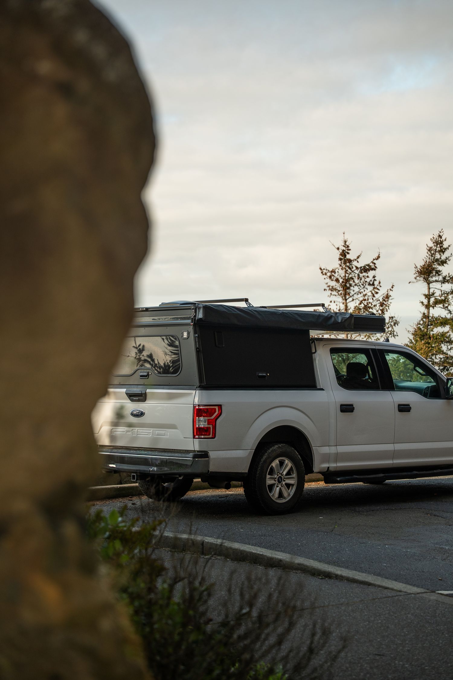 White Ford F-150 truck parked on scenic overlook with rock formation in foreground.