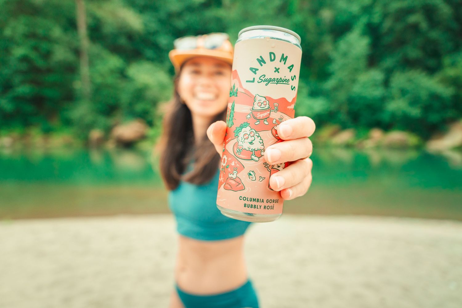 Woman holding a Grandma's Superbrew Columbia Hops Barely Beer can outdoors by a river.