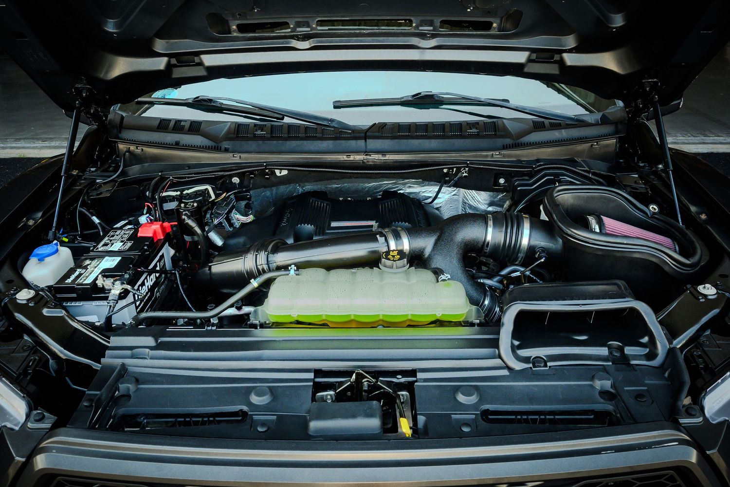Close-up view of a high-performance truck engine bay with aftermarket cold air intake and yellow air filter.