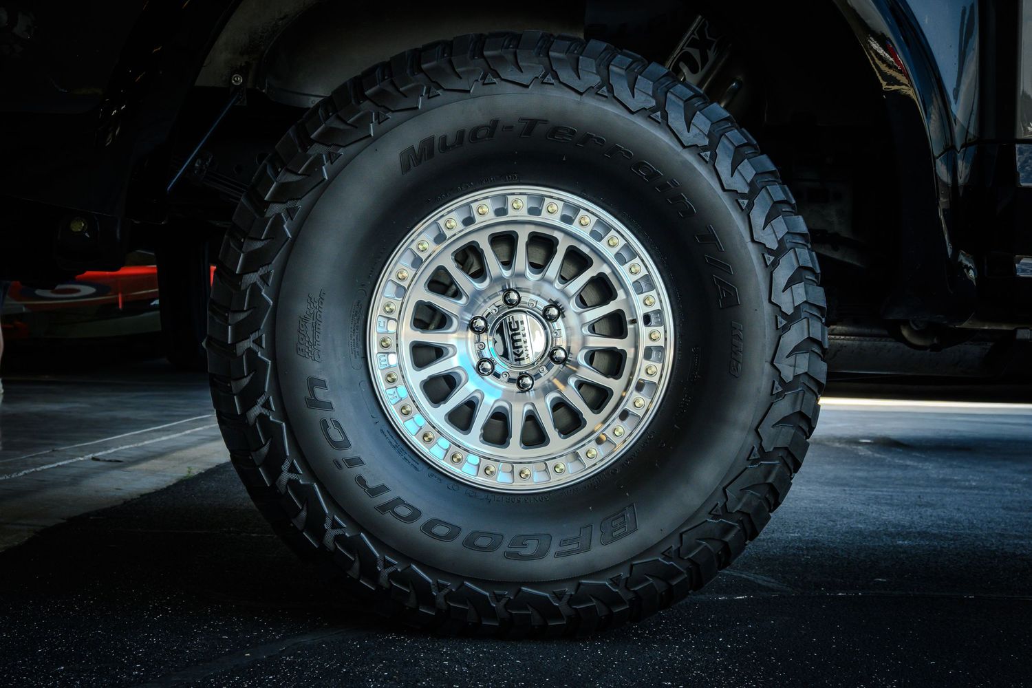 BFGoodrich all-terrain tire on a silver beadlock wheel with blue accents on a dark off-road truck.