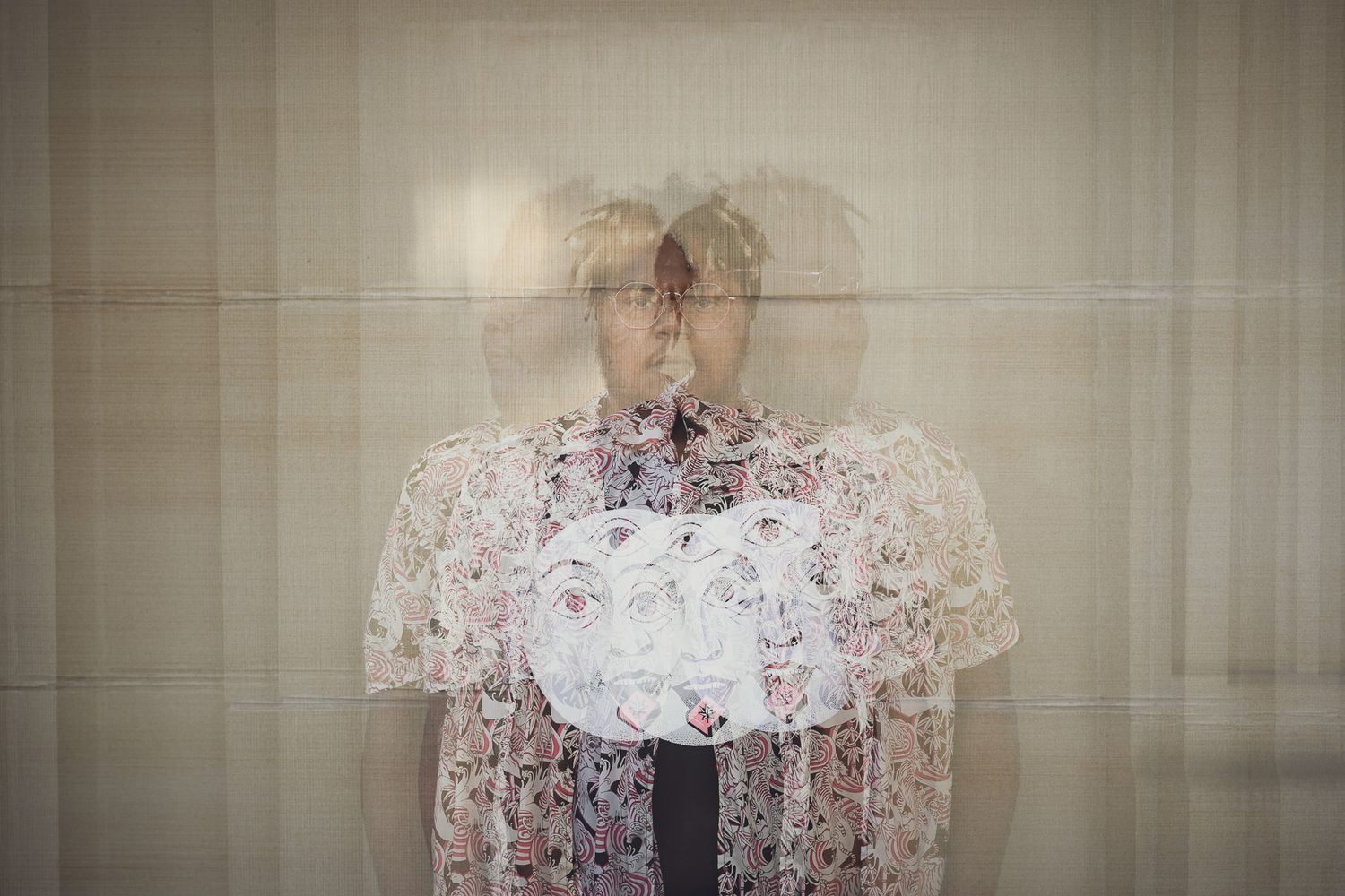 Artistic double exposure portrait of a person in floral top against neutral background.
