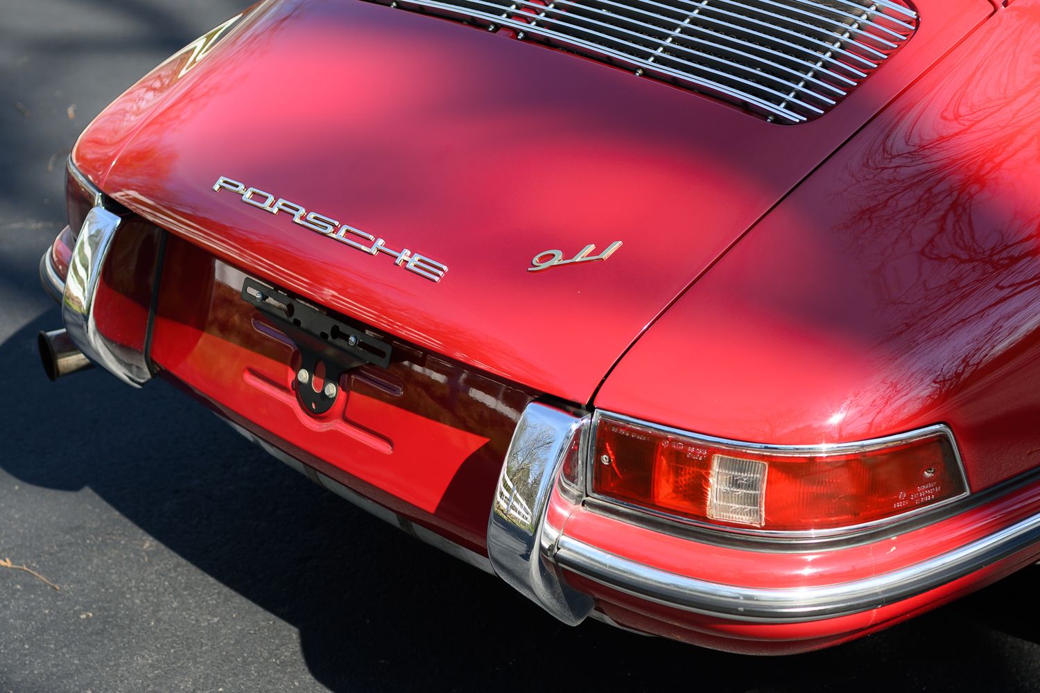 Rear view of a vintage red Porsche 911 showing iconic taillights, chrome bumper, and Porsche badge.