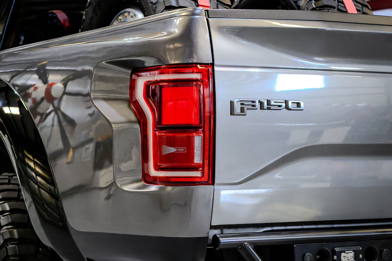 Close-up of a silver Ford F-150 truck taillight and badge on the rear panel.