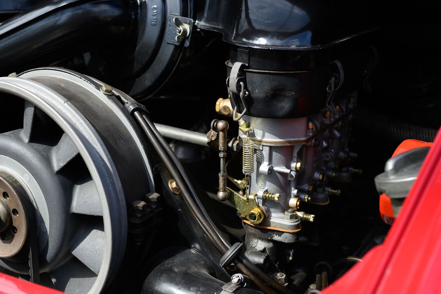 Detailed view of a vintage Porsche 911 air-cooled flat-six engine with carburetor and mechanical components.
