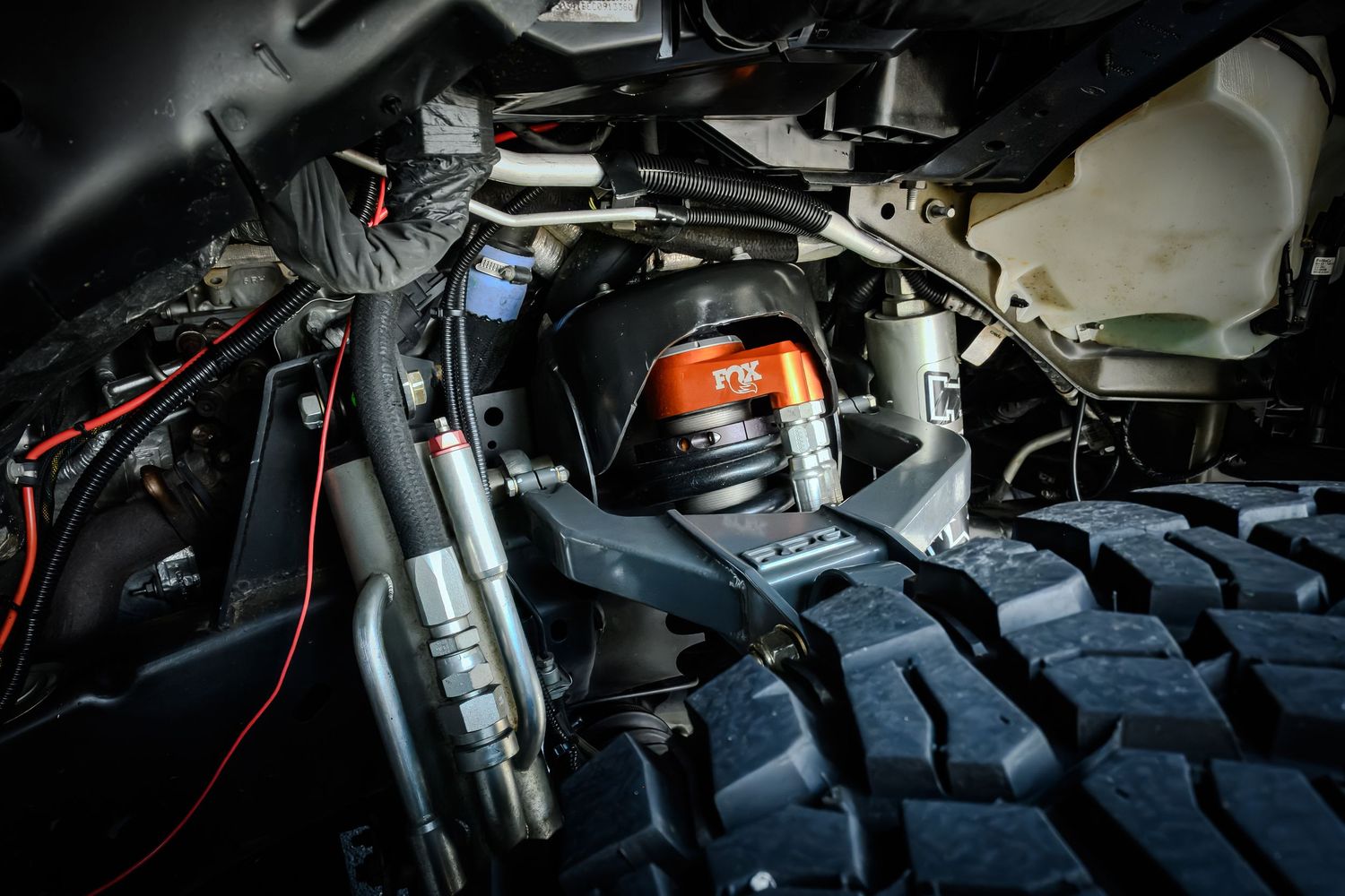 Close-up of a heavy-duty off-road vehicle suspension system with coilover shocks and large knobby tires.