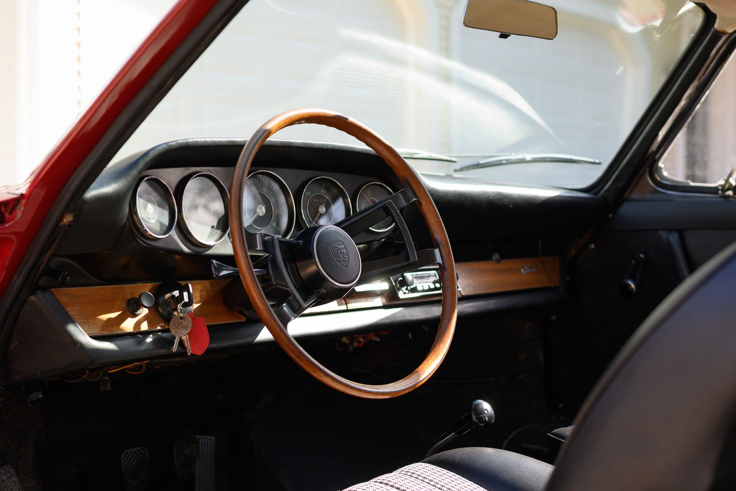 Interior view of a classic Porsche 911 featuring a wooden steering wheel and vintage dashboard gauges.