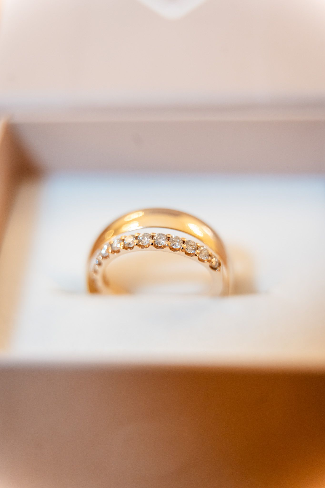 Gold wedding band with diamond accents displayed in a jewelry box.