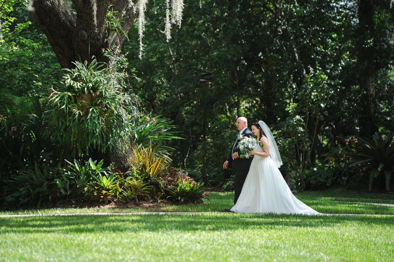Bride and groom share a romantic kiss in a lush green garden during their outdoor wedding ceremony.