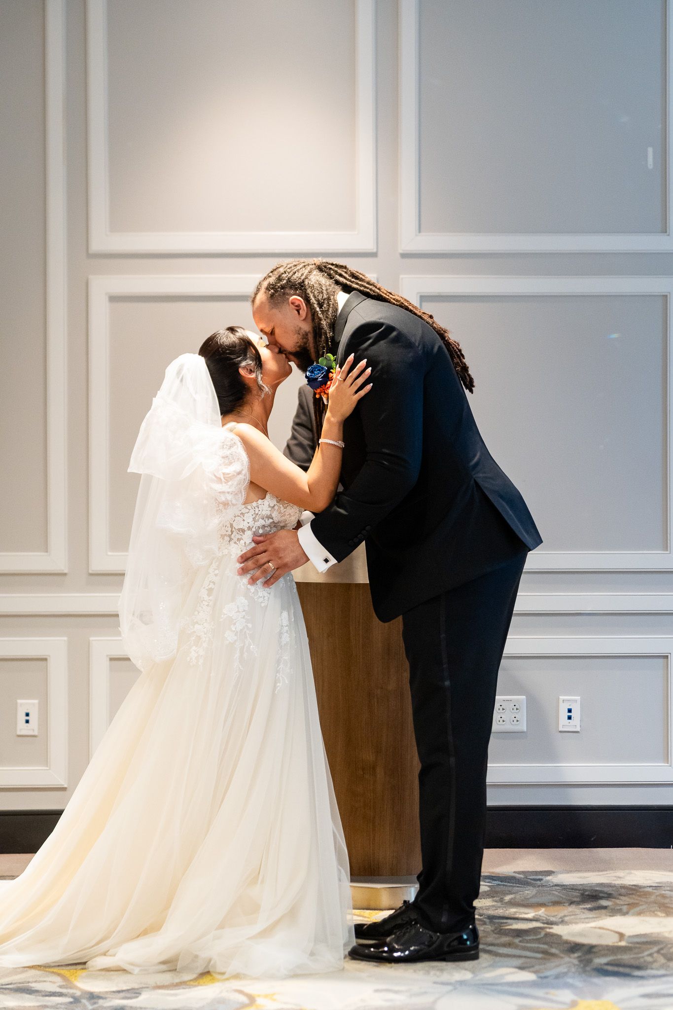 Bride and groom share first kiss at wedding ceremony altar.