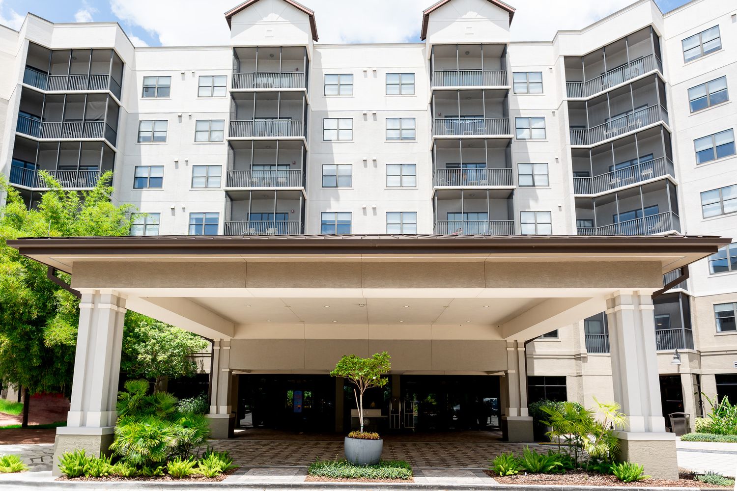 Multi-story hotel building with covered entrance portico and manicured landscaping.