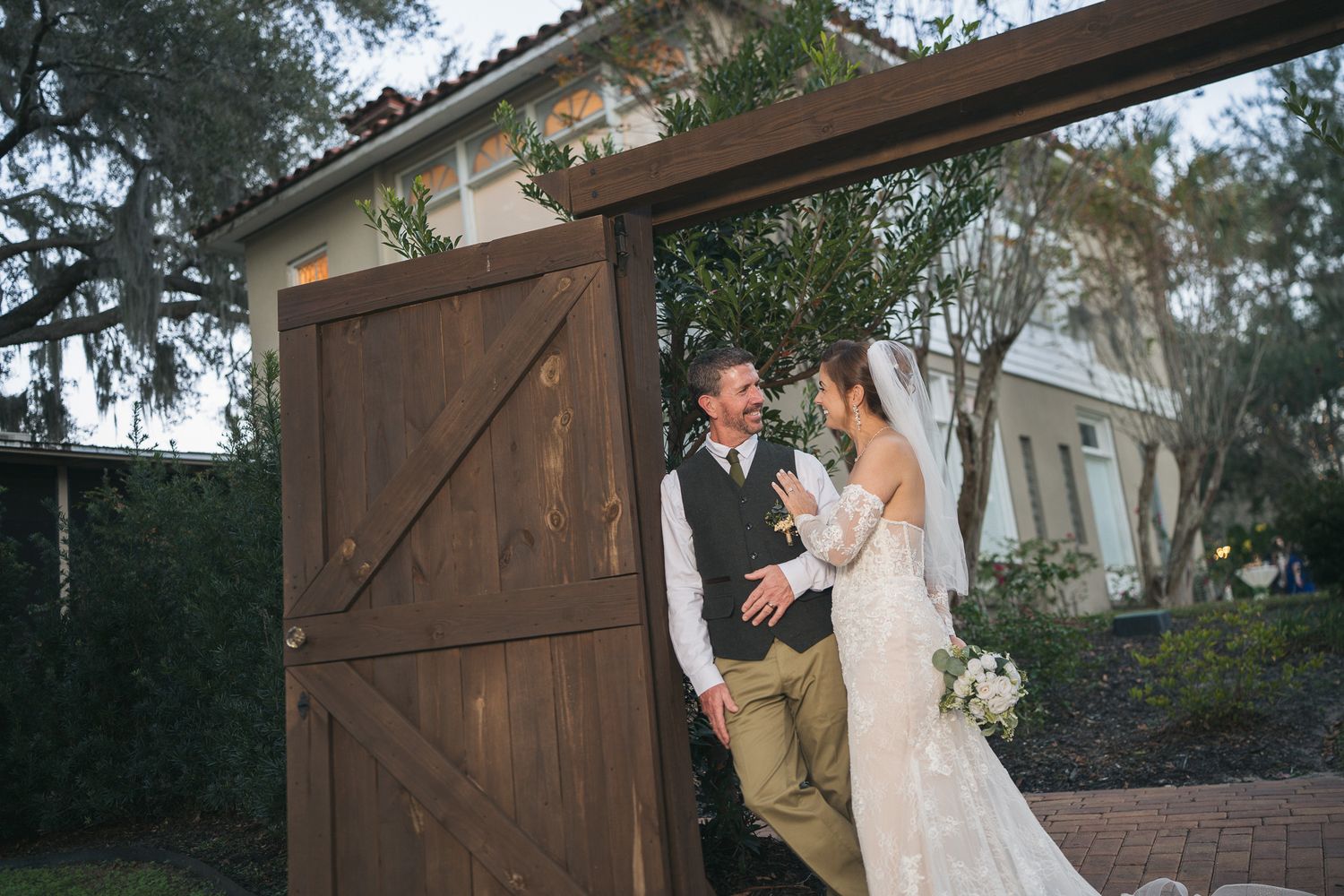 Bride and groom share a joyful moment by rustic wooden barn doors at their wedding venue.
