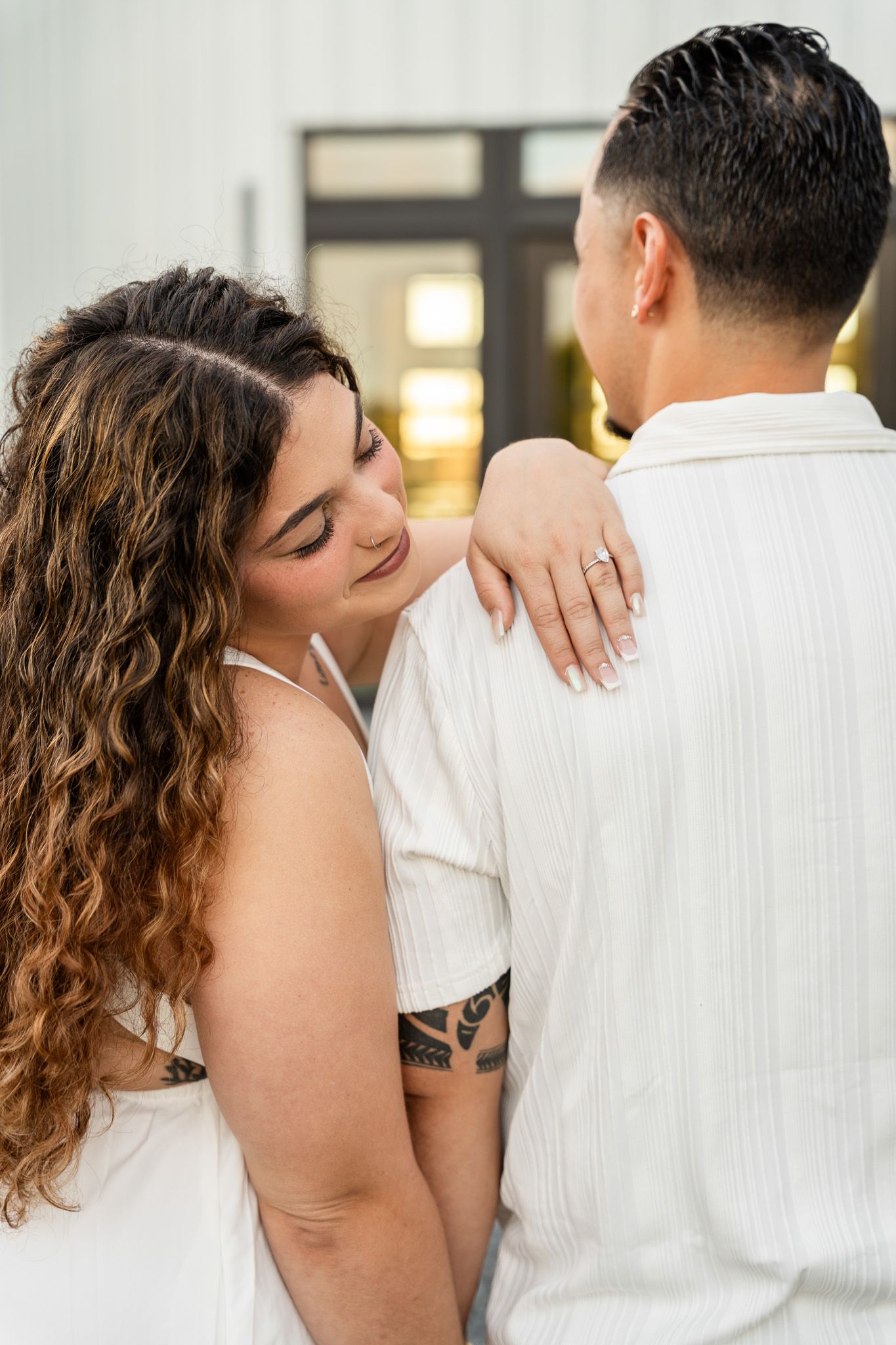 Woman resting her head on her partners shoulder, showing off her engagement ring during a couples session.