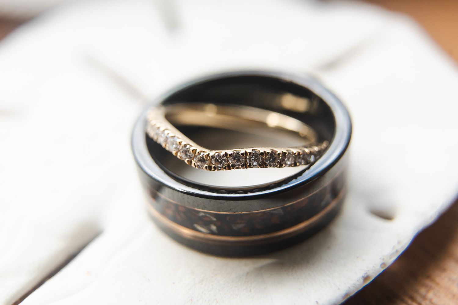 Close-up of elegant wedding bands, including a diamond eternity band and a dark carbon fiber ring.